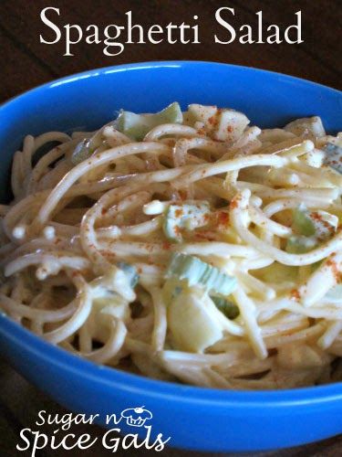 spaghetti salad in a blue bowl on a wooden table with text overlay that reads, spaghetti salad