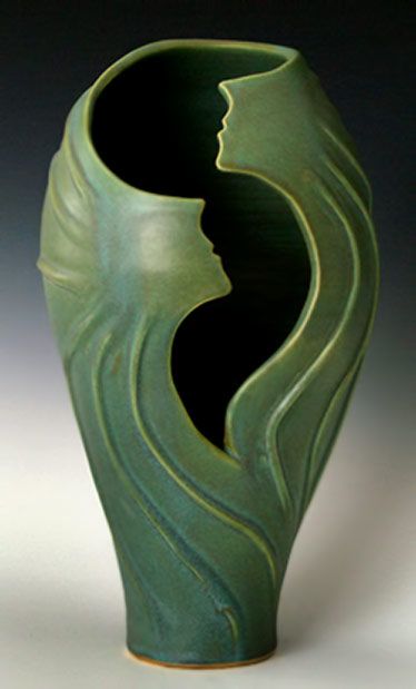 a green vase with two faces on it