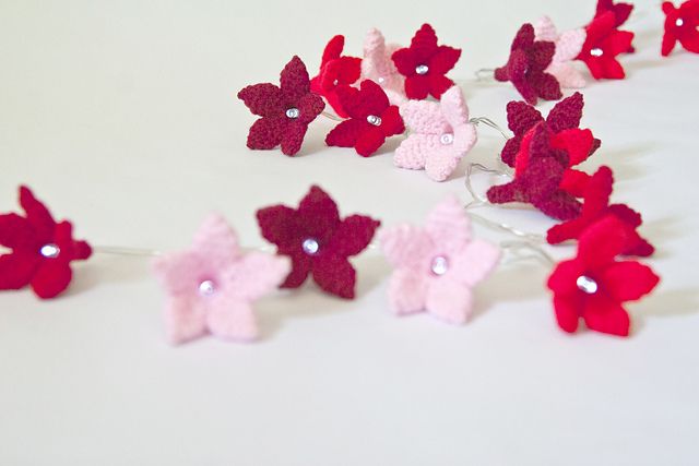 red and pink crocheted flowers on a white surface