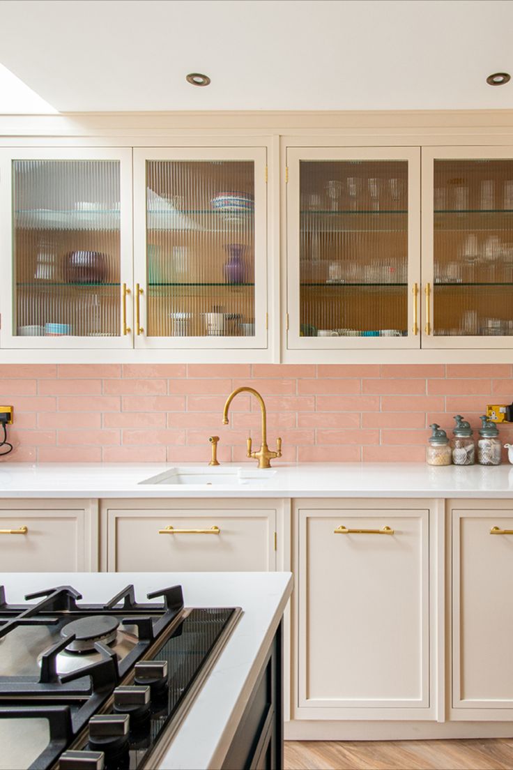 a kitchen with white cabinets and pink backsplash