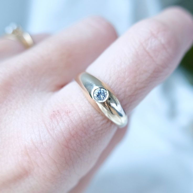 a close up of a person's hand wearing a ring with a diamond on it