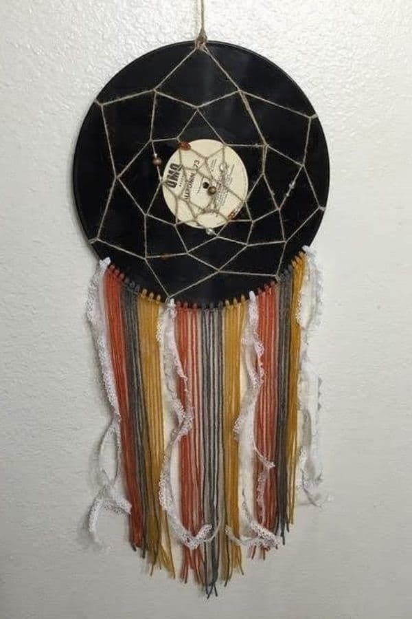 a black, white and orange dream catcher hanging from a wall with beads on it