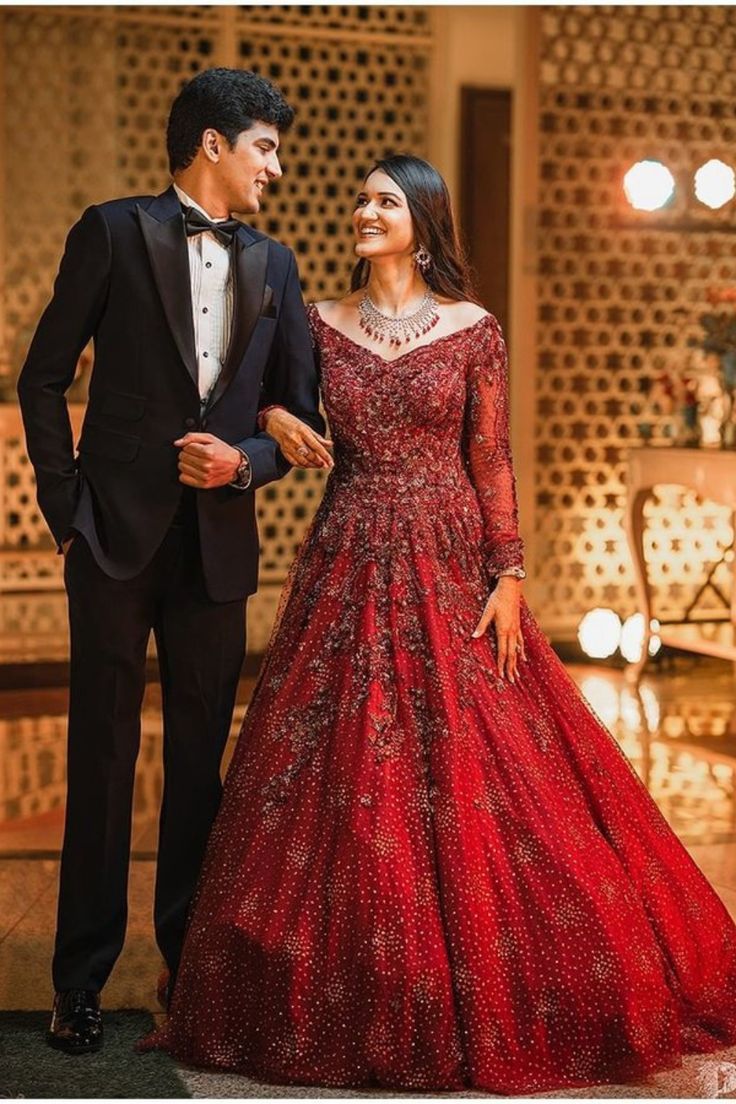 a man in a tuxedo standing next to a woman in a red gown