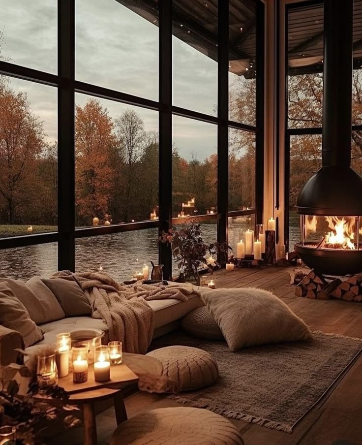 a living room filled with lots of furniture and candles in front of large glass windows