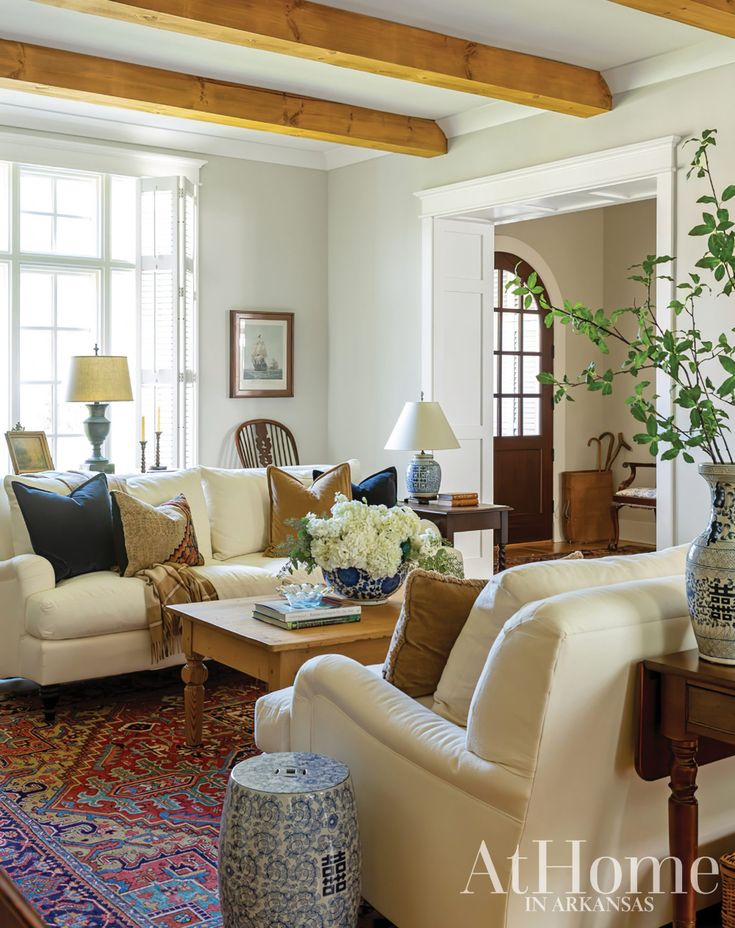 a living room filled with lots of furniture and flowers in vases on the coffee table