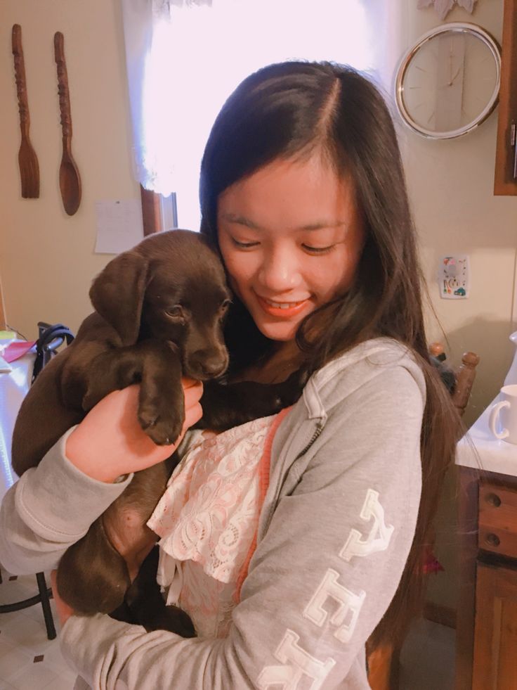 a woman holding a puppy in her arms