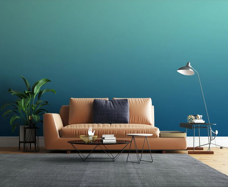 a living room with a couch, table and lamp on the floor in front of a blue wall