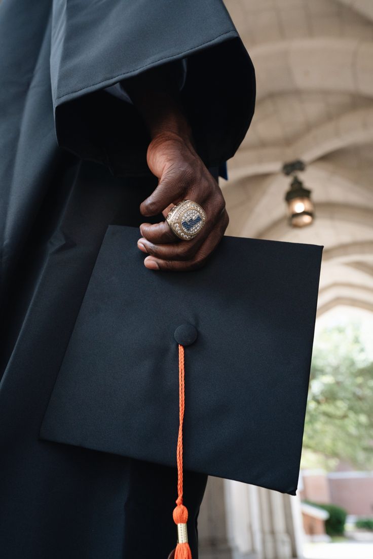 a person wearing a graduation cap and gown with a tassel on their left hand