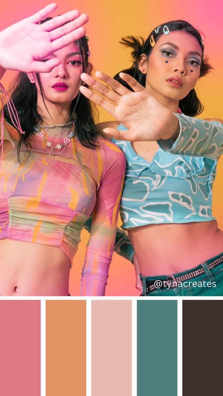 two women are posing in front of a colorful background with their hands up to the camera