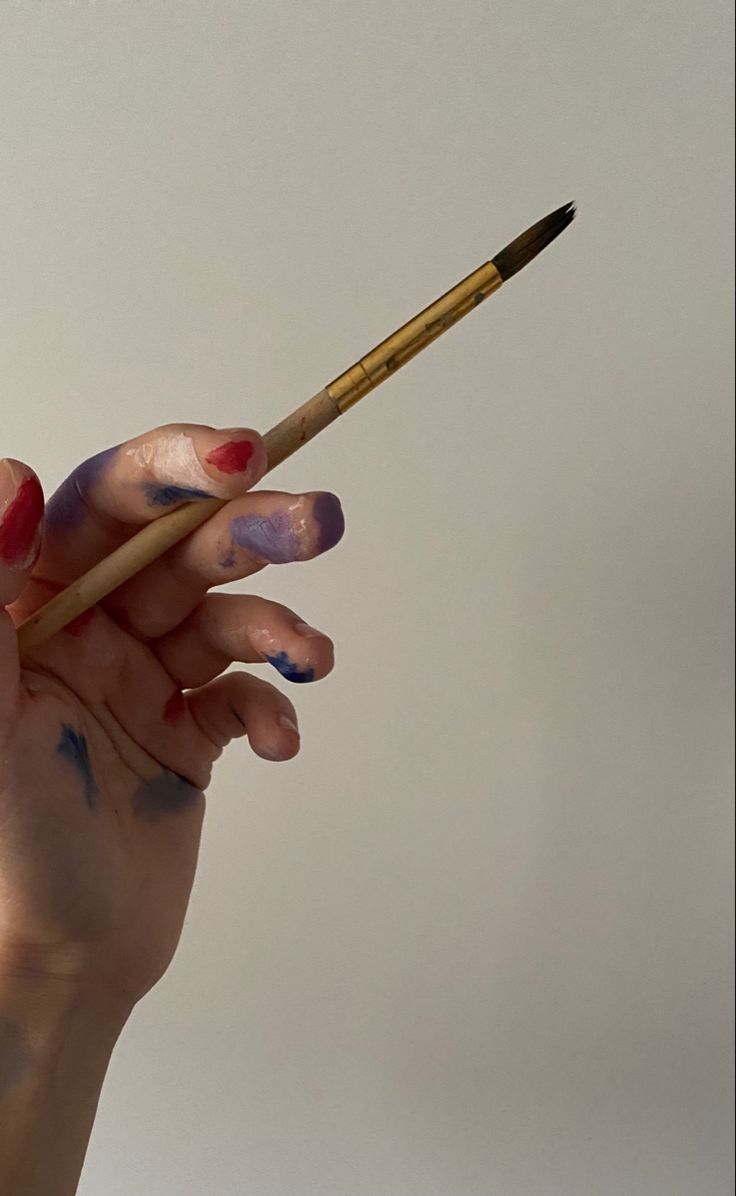 a woman's hand holding a paintbrush in the air