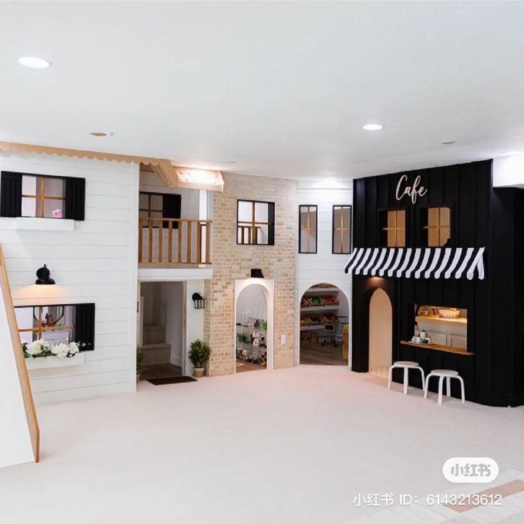 the inside of a dollhouse with black and white walls, windows, and stairs