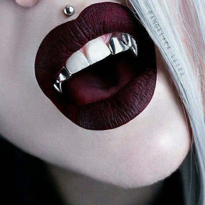 a close up of a woman's mouth with metal decorations on it and teeth