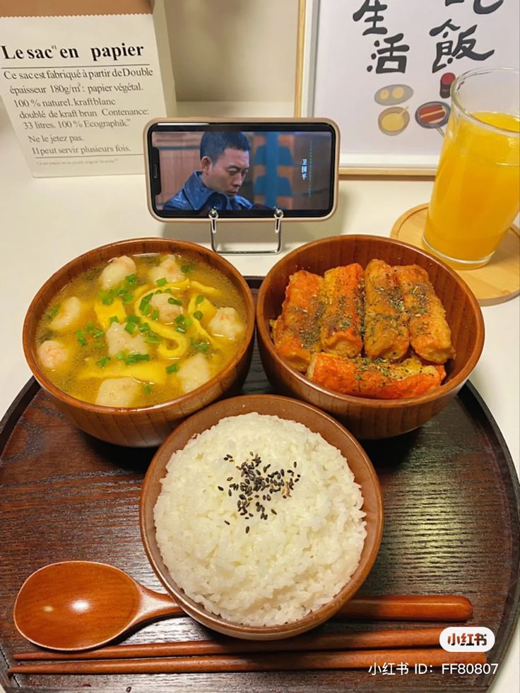 there are three bowls of food on the table with a cell phone next to it