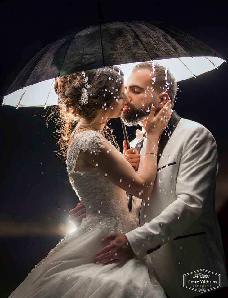 a bride and groom kissing under an umbrella