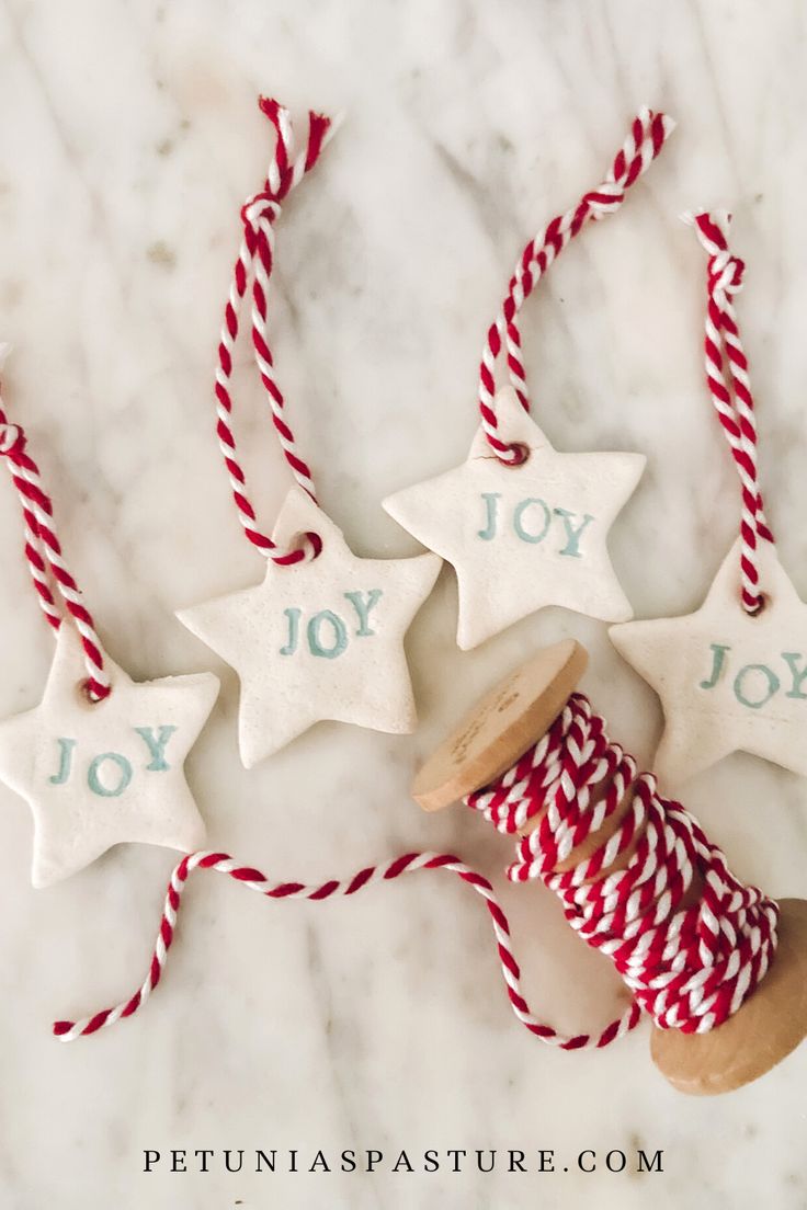 three christmas ornaments with red and white twine on them, one has joy written on it