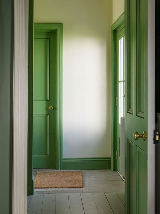 an empty hallway with green doors and white walls