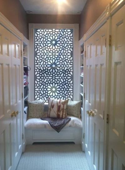 the hallway is decorated with white doors and decorative window panels, along with a bench that has pillows on it