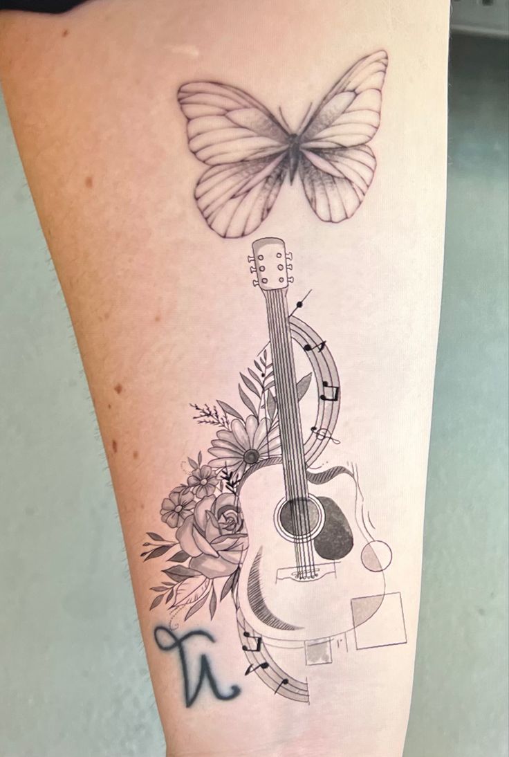 a tattoo on the leg of a woman with a guitar and flowers in front of a butterfly