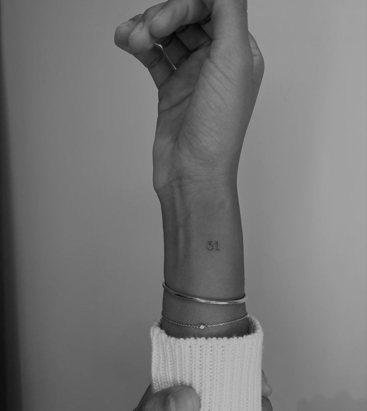 a woman's wrist tattoo with the number thirteen on her left hand, in black and white