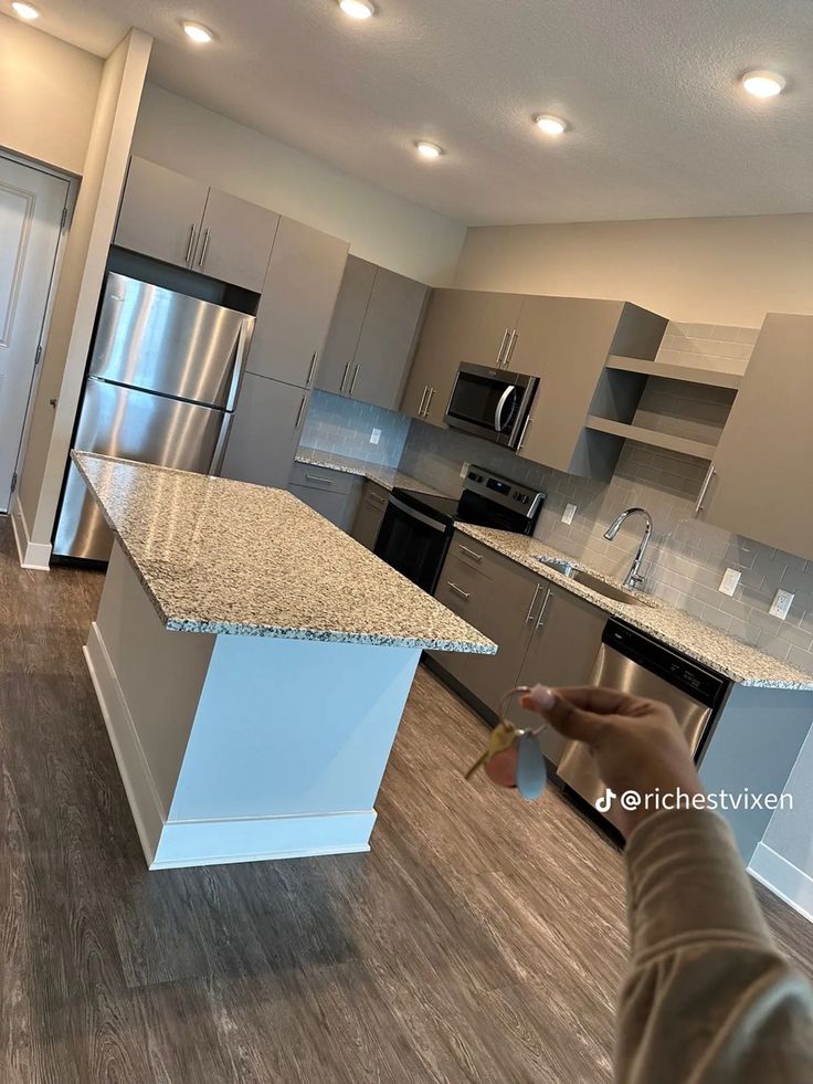 a person is taking a photo of a kitchen with granite counter tops and stainless steel appliances