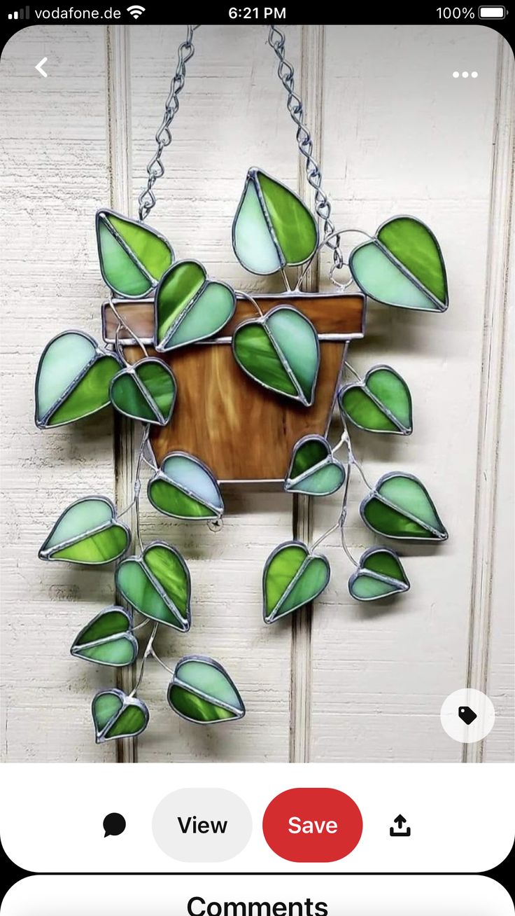 a green and white stained glass sun catcher hanging from a hook on a wooden door