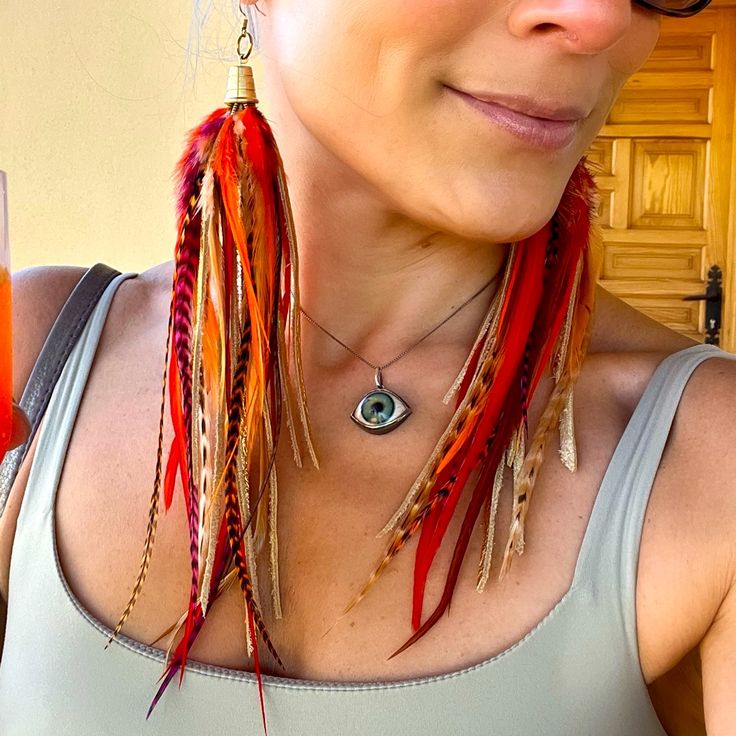 a woman with red and brown feathers on her neck wearing sunglasses, necklace and earrings