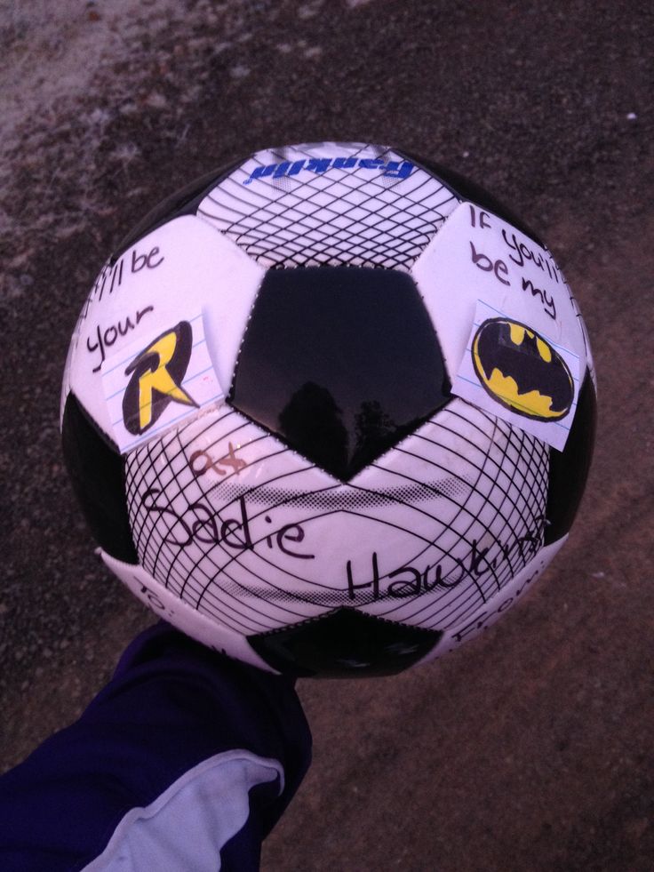 a close up of a person holding a soccer ball with batman stickers on it