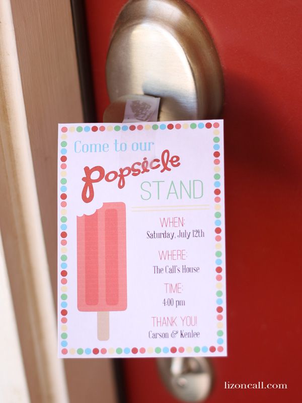 a pink popsicle stand sign hanging from a door handle on a red front door