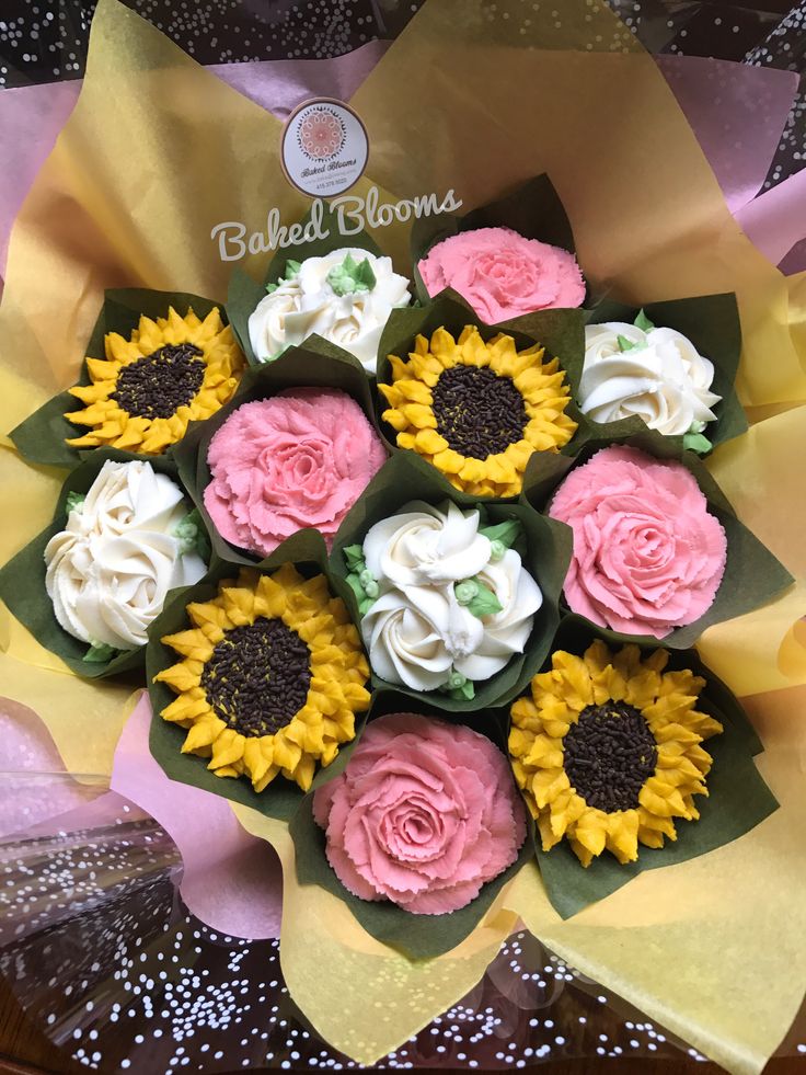 a bouquet of sunflowers and cupcakes in pink, yellow and white