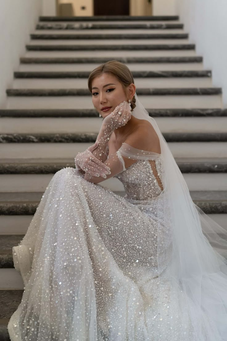 a woman in a wedding dress sitting on the steps with her hand near her face