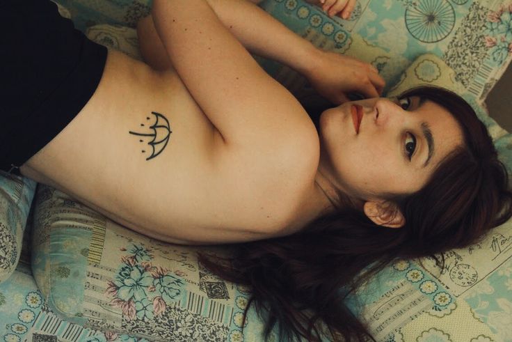 a woman laying on top of a bed with a tattoo on her stomach