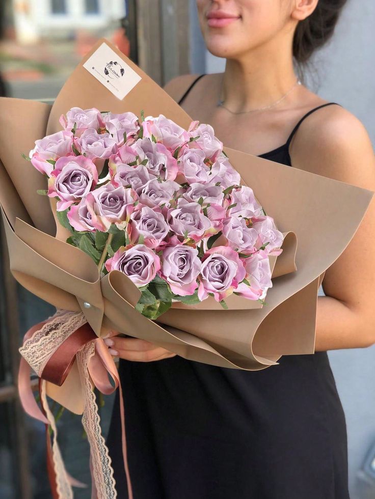 a woman holding a bouquet of purple roses