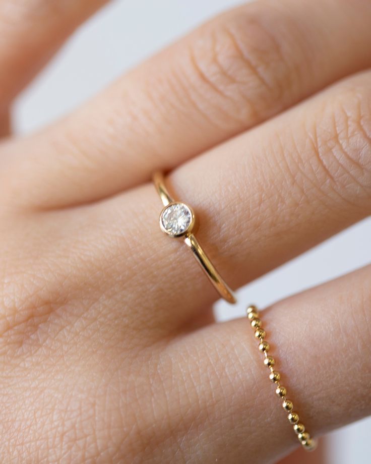 a woman's hand with a diamond ring on her left hand and a yellow gold band