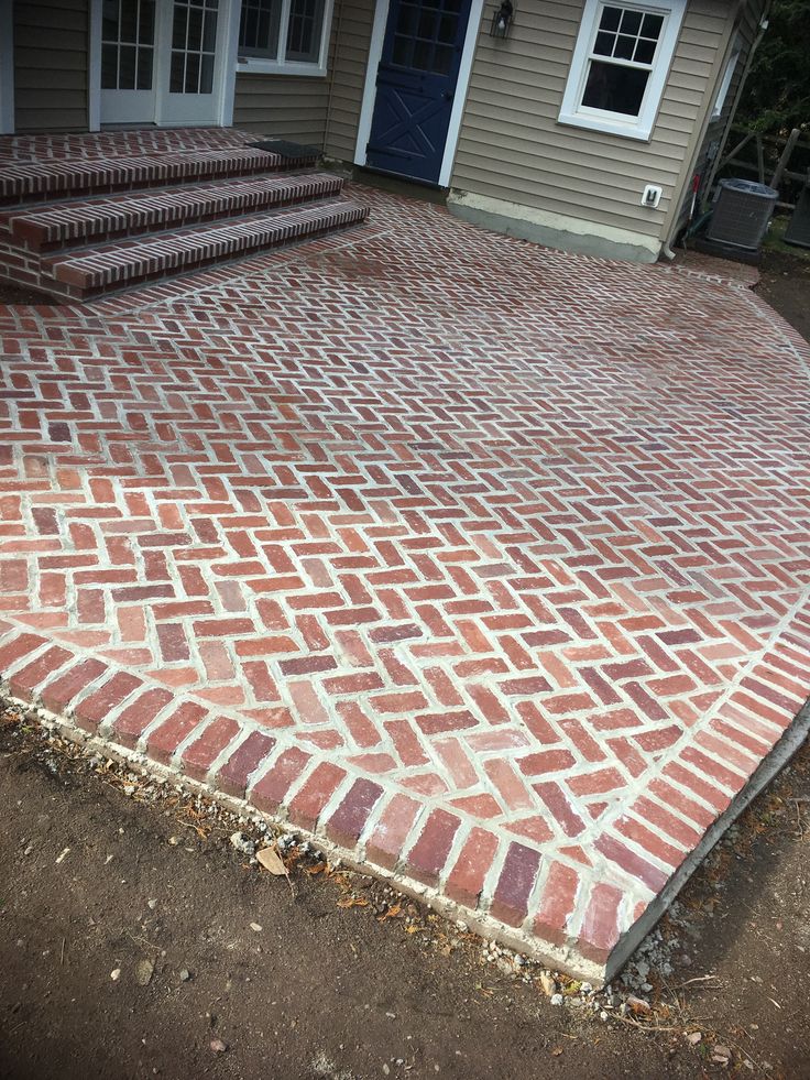 a brick patio with steps leading up to the front door