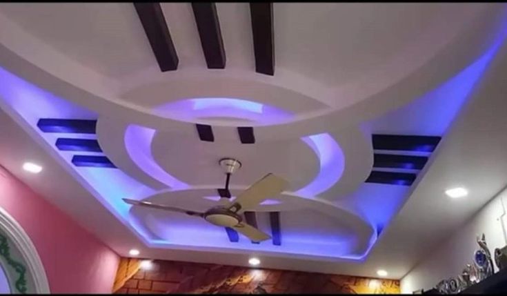 the ceiling is decorated with blue lights and white paint on it, along with a fan