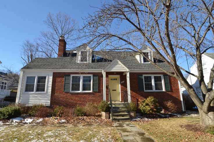 a red brick house with snow on the ground and trees in front of it,