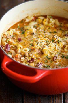 a red pot filled with macaroni and cheese on top of a wooden table