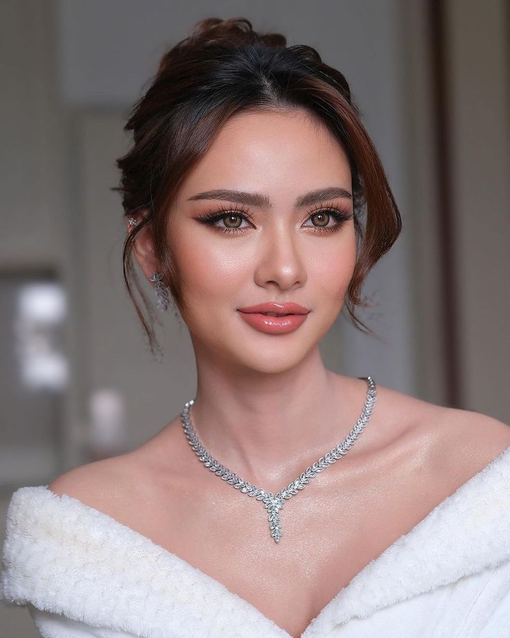 a woman in a white dress wearing a diamond necklace