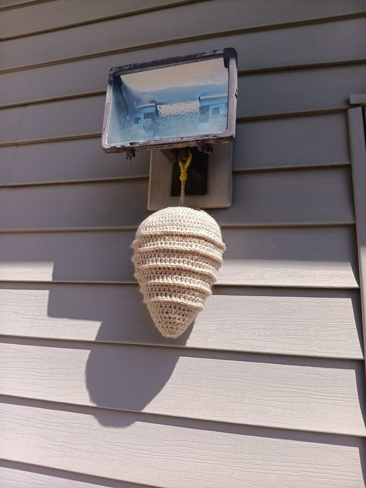 a white object hanging from the side of a house next to a light on a wall