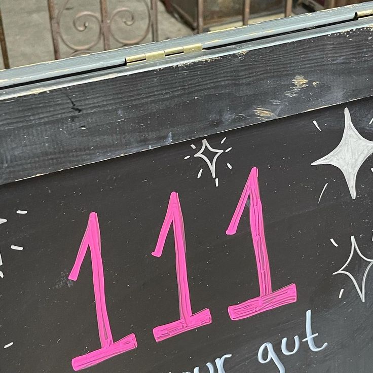 a chalkboard sign with the number 11 and year out written in pink on it