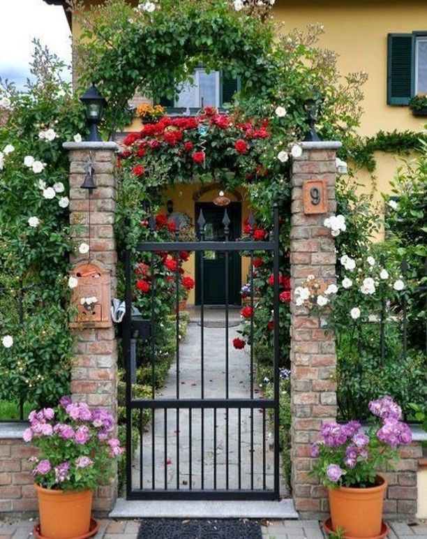 an iron gate surrounded by flowers and potted plants