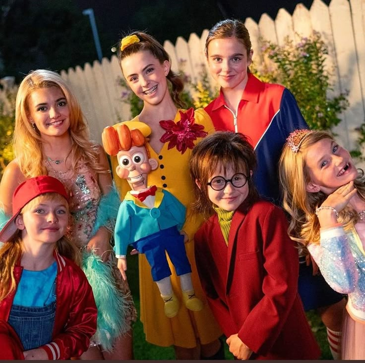 a group of people standing next to each other in front of a white picket fence