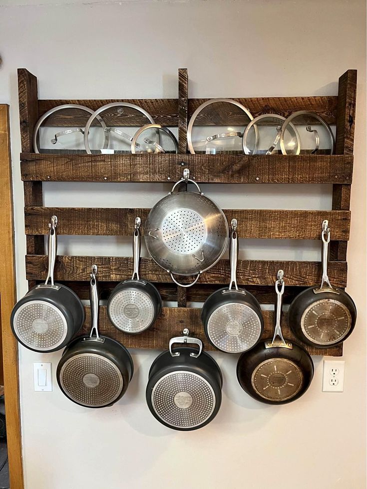 pots and pans are hanging on the wall in front of an old rack that is made out of pallets