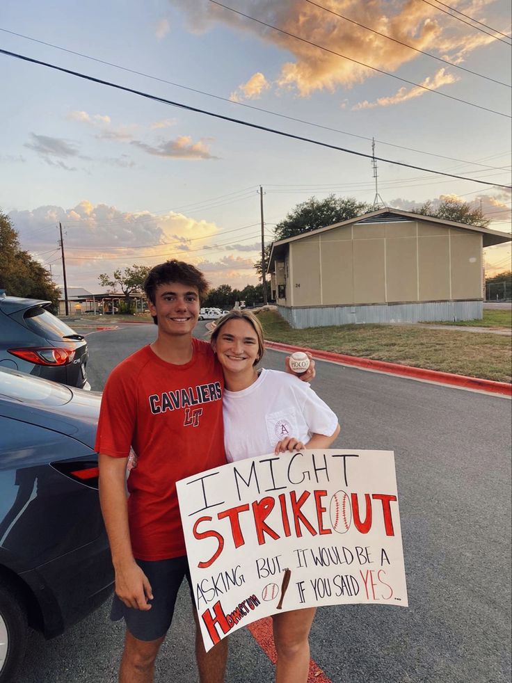 a man and woman standing next to each other holding a sign