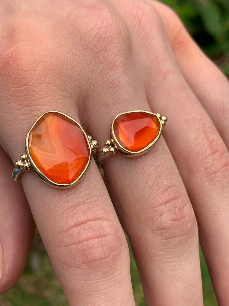 The incredible texture in this striped Rosecut Carnelian is truly one of a kind. Like a flowing river of orange lava it is set in 14k yellow gold with accent beads and a freeform sterling silver band. Approximate stone size: 14mm x 17mm 5.8 cts Mohs Stone Hardness: 6 This one of a kind piece is handmade to in Emily's Hudson Valley studio. This piece is in stock and can be resized prior to shipping. If you have questions about sizing, shipping or need help deciding please reach out to us! Luxury Carnelian Ring Jewelry, Unique Carnelian Ring Jewelry, Unique Round Carnelian Jewelry, Unique Silver Carnelian Rings, Red Polished Carnelian Rings, Flowing River, Orange Gem, Orange Stone, Local Jewelry