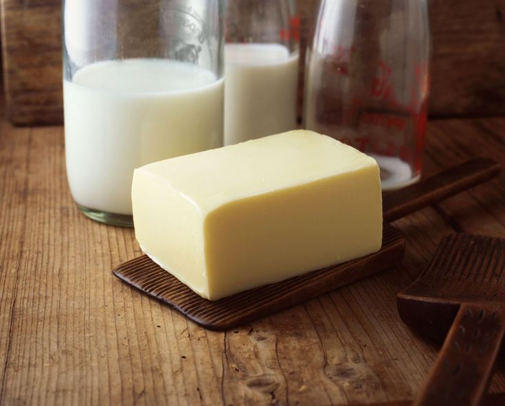 a block of butter next to two glasses of milk