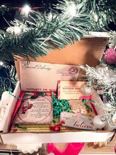 a christmas tree with ornaments and cards in a box on the bottom shelf next to it