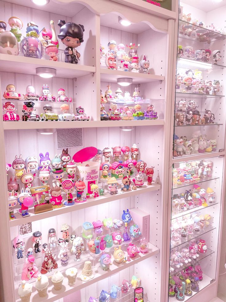 a display case filled with lots of different types of toys and dolls on shelves next to each other