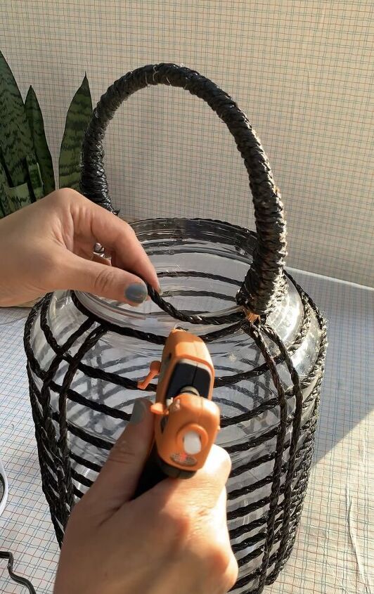 a person holding a small object in their hand near a wire basket on a table