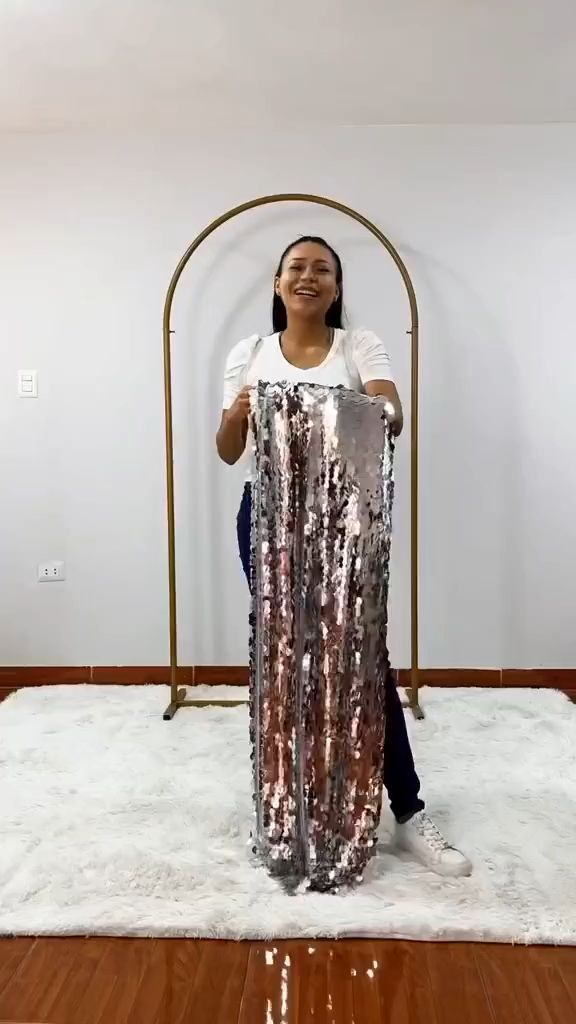 a woman standing on top of a white rug in front of a metal pole with a large piece of tin foil covering it